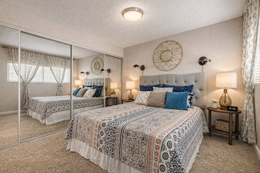 A bedroom with two beds and a mirror. at Infinity on the Landing Apartments , Texas