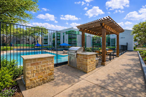 A pool area with a wooden pergola and a black fence. at Infinity on the Landing Apartments , Texas