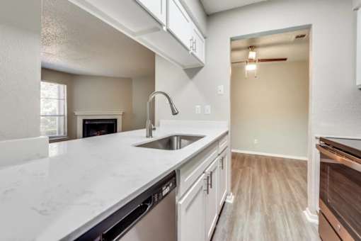 A kitchen with a white counter top and a stainless steel dishwasher at Infinity on the Oaks Apartments, Texas, 75231