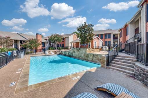 A swimming pool surrounded by a fence and steps leading to a building at Infinity on the Oaks Apartments , Texas, 75231