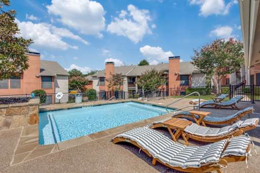 A pool surrounded by lounge chairs and a fence at Infinity on the Oaks Apartments , Dallas, TX