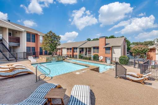 A sunny day at a poolside with lounge chairs and a clear blue sky at Infinity on the Oaks Apartments , Dallas, Texas
