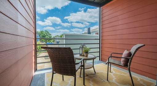 A balcony with a chair and table overlooking a building at Infinity on the Landing Apartments, Texas, 76040