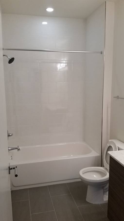 A white toilet sits in a bathroom next to a white bathtub.