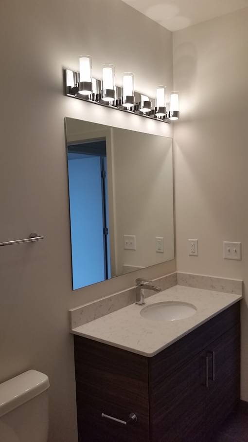A bathroom with a sink, mirror, and light fixture.