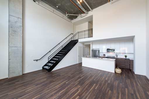 A black metal staircase with a wooden floor leading to a kitchen area.
