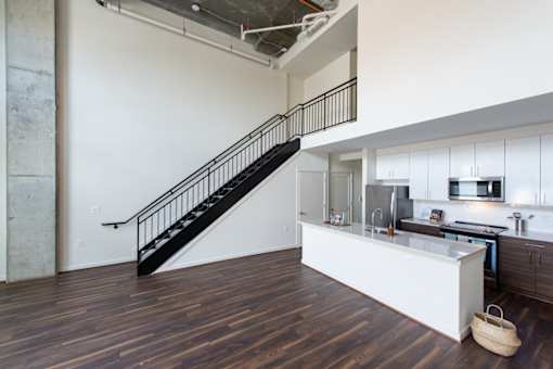 A kitchen with a staircase in the middle of it.
