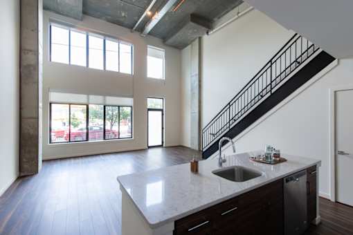 A kitchen with a marble counter top and a stainless steel dishwasher.