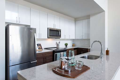A kitchen with a refrigerator, microwave, and a sink.