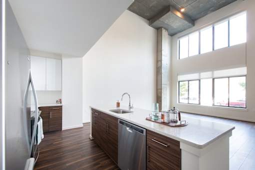 A kitchen with a white counter top and a dishwasher.