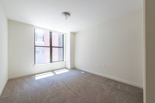 A room with a carpeted floor and a window.