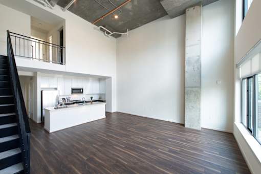 A large open space with a staircase on the left and a kitchen area in the middle.