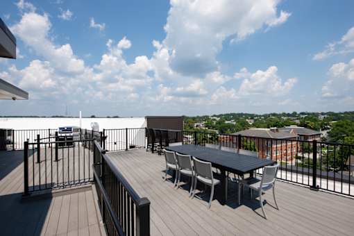 A balcony with a table and chairs overlooking a cityscape.