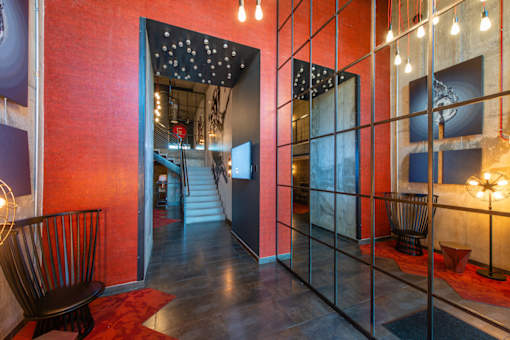 A hallway with a red wall and a black chair.