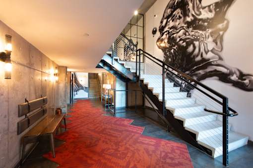 A staircase with a red carpeted floor and a wall mural of a man's face.