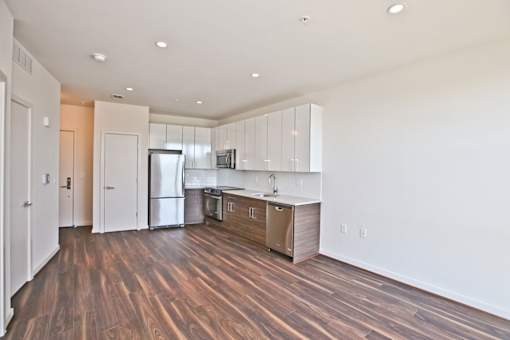 A kitchen with white cabinets and a wooden floor.