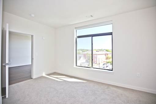 A spacious room with a large window overlooking a residential area.