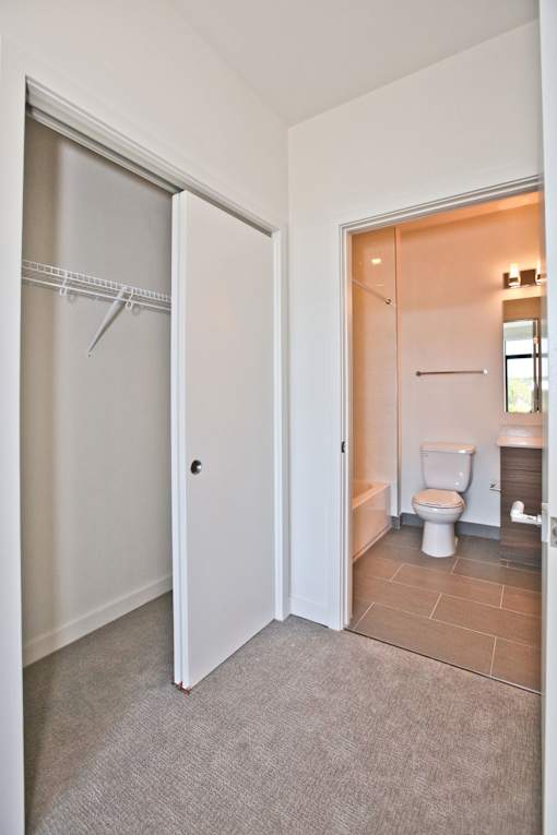 A white door is open to a bathroom with a toilet and sink.