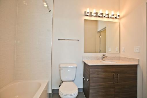 A white toilet sits next to a white bathtub in a bathroom.