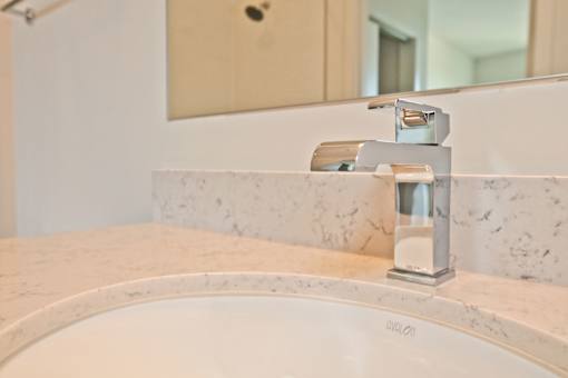 A white sink with a faucet on a marble countertop.