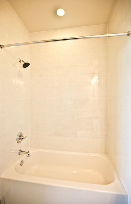 A white bathtub with a shower head above it.