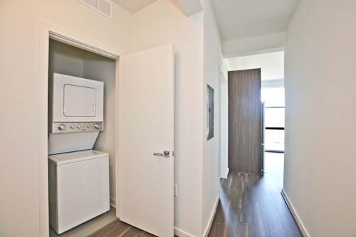 A white dryer is built into a wall in a hallway.