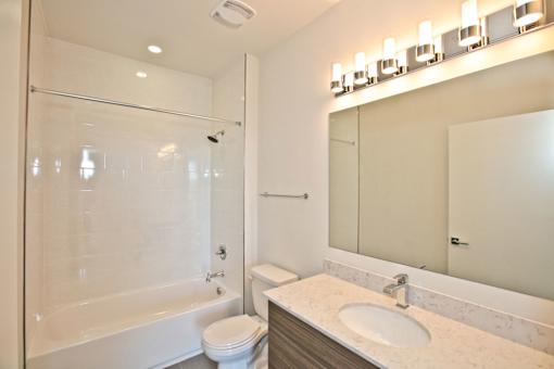 A white bathroom with a toilet, sink, and mirror.