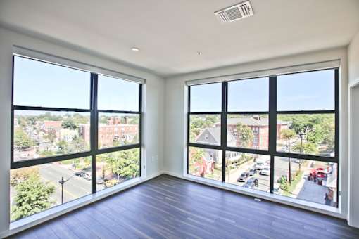 A room with a view of a street and buildings outside.