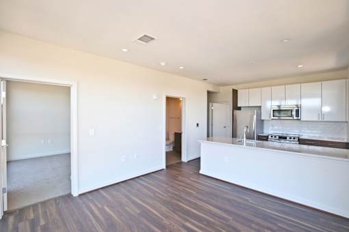 A kitchen with a white counter and wooden floors.