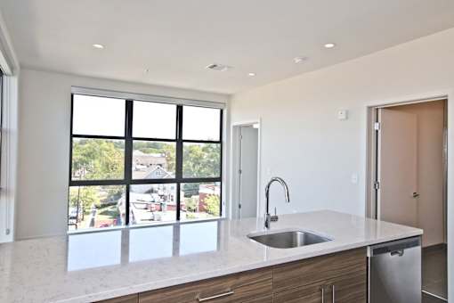 A kitchen with a sink and a window overlooking a street.
