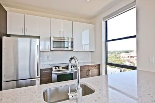 A modern kitchen with stainless steel appliances and a marble countertop.