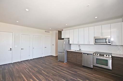 A kitchen with white cabinets and a wooden floor.