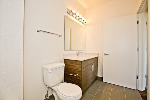 A white toilet is in a bathroom with a wooden vanity and a mirror.