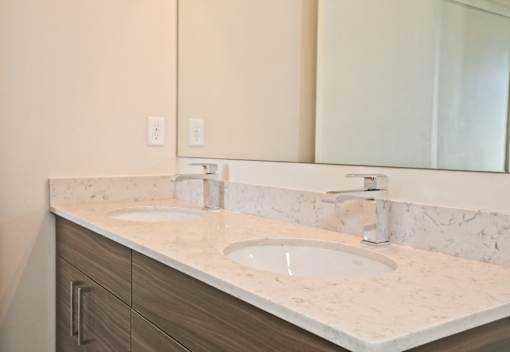 A bathroom counter with two sinks and a mirror.