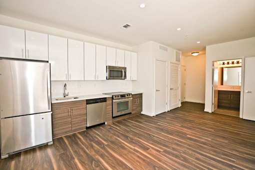 A kitchen with a refrigerator, microwave, oven, and cabinets.