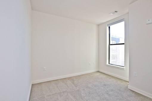 A room with a window and a carpeted floor.