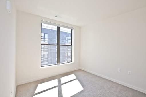 A room with a large window and a carpeted floor.