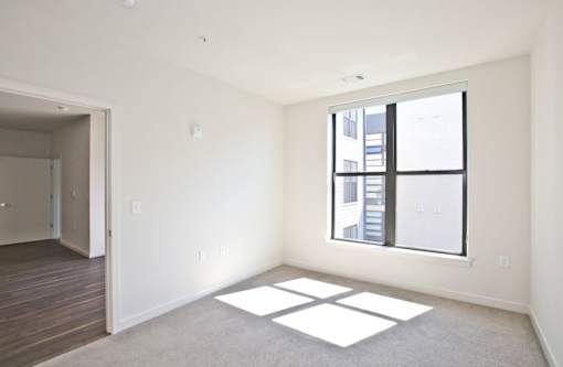A room with a large window and a view of a building outside.