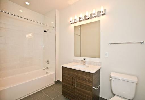 A bathroom with a white toilet, a sink, a mirror, and a shower.