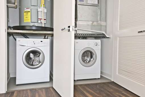 Two white front loading washing machines in a small laundry room.