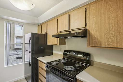 A kitchen with a black stove and wooden cabinets.
