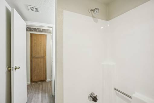 A white bathroom with a door and a shower.