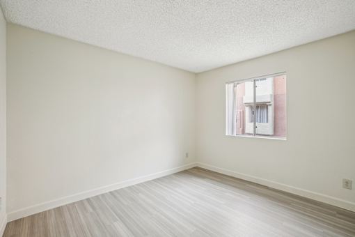 A room with a window and wooden flooring.