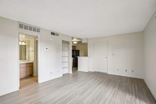 A large empty room with wood flooring and white walls.
