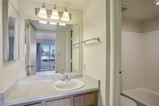 A bathroom with a sink, mirror, and tub.