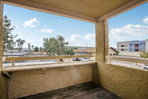 A balcony with a view of a parking lot and buildings.