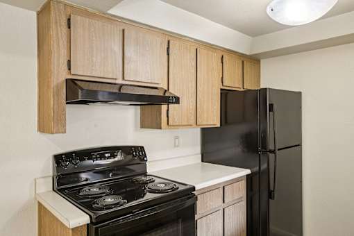 A kitchen with a black stove and black refrigerator.