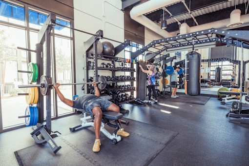 A man is working out in a gym with a barbell.