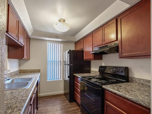 A kitchen with brown cabinets and granite countertops.