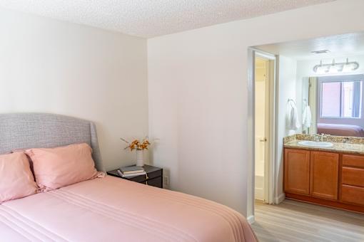 A bedroom with a pink bedspread and a grey headboard.